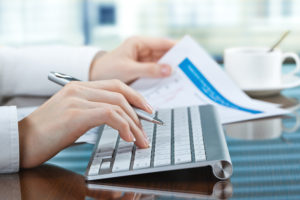 Dental Office Accounts Receivable Require Your Full Attention. A Woman's Hands on the keyboard and holding a calendar represent a dental office team member working the acounts receivable