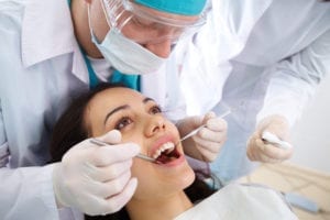 A healthy female dental patient is having her dental cleaning. Learning dental hygiene scheduling also requires an understanding of different types of hygiene visits.
