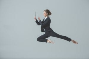 A business woman is leaping for joy with her computer as she is improving dental customer service and is having a much better day.