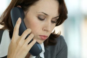 A businesswoman talks on the phone as she is working overdue patient accounts