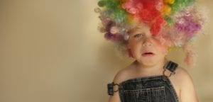 A young child cries and wears a clown wig. He's having a bad day and represents a bad day. Difficult dental patient situations often result from a "bad day".