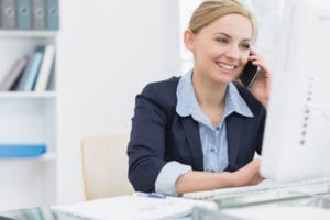 A dental office team member talks on the telephone and works at the computer